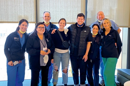 Evan Rood and his younger sister Mica pose with some of his former care providers on the ICU floor.